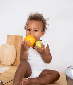 Black baby holding fresh fruit